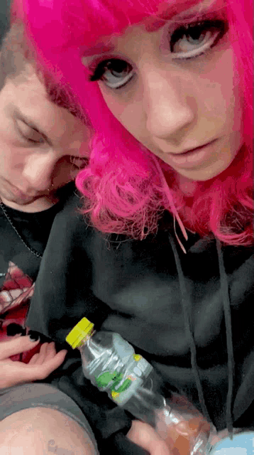 a woman with pink hair is holding a bottle that says gatorade on it
