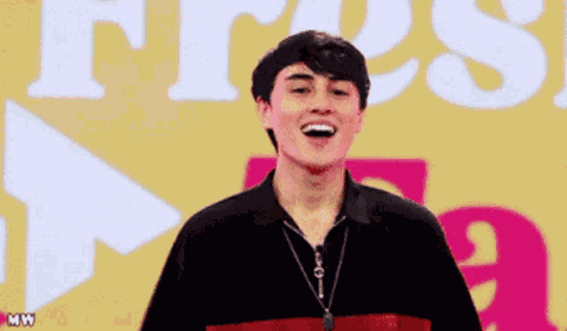 a young man is smiling in front of a sign that says " fresh "