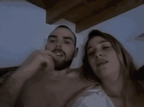 a man and woman are laying on a bed and the woman is smiling