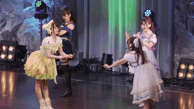 a group of girls are dancing on a stage with lights behind them