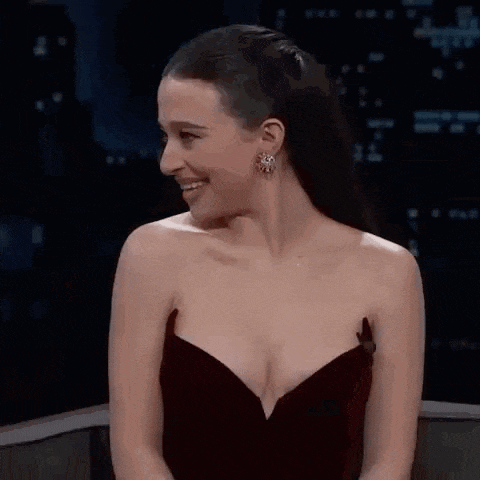 a woman in a strapless dress is smiling while sitting on a chair .