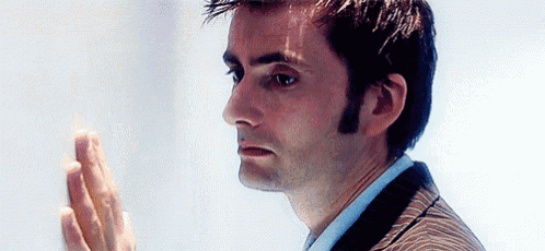 a close up of a man 's face with his hand on a white wall .