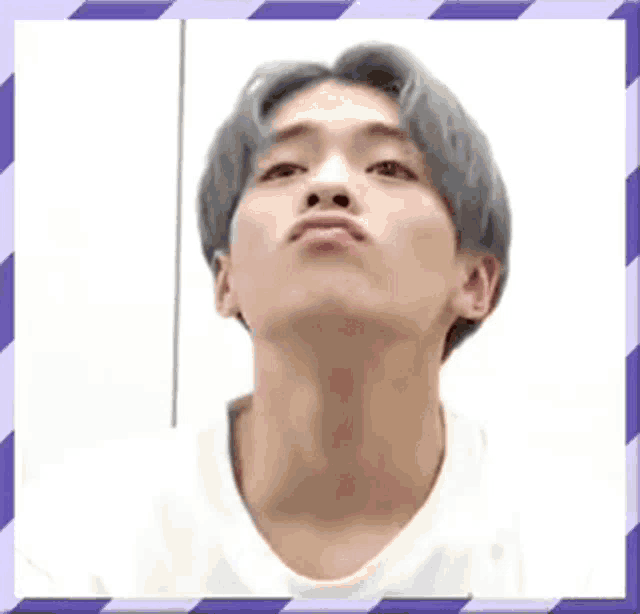 a young man with gray hair and a white shirt is making a funny face with his mouth open .