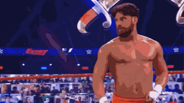 a man without a shirt is standing in a boxing ring with swords behind him