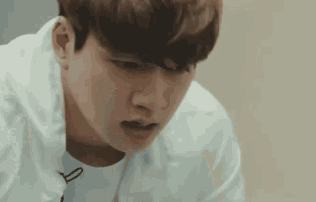 a young man in a white shirt is looking down .