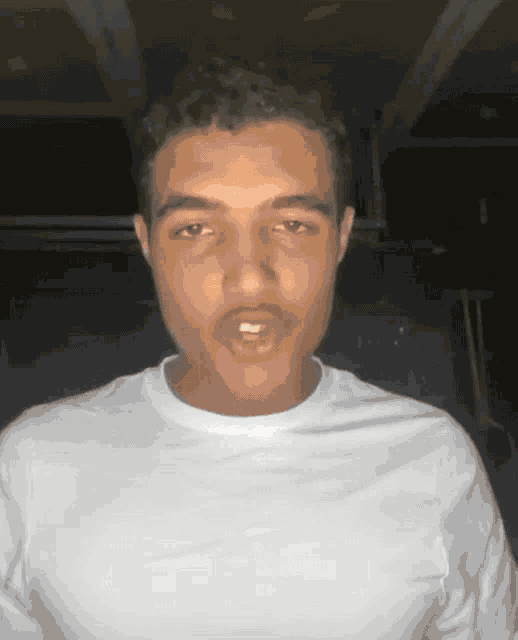 a young man in a white shirt is making a face
