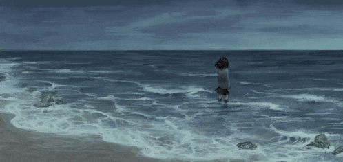 a girl is standing in the ocean on a beach