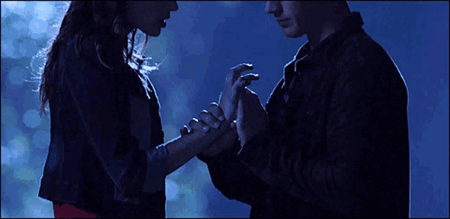 a man and woman holding hands in the dark