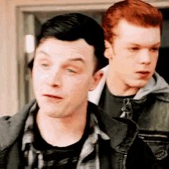 a couple of men are standing next to each other and one of them has red hair .