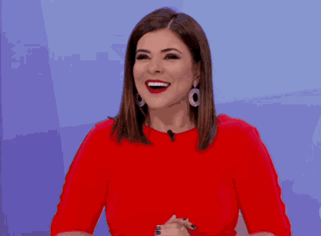 a woman in a red shirt is laughing with a blue background