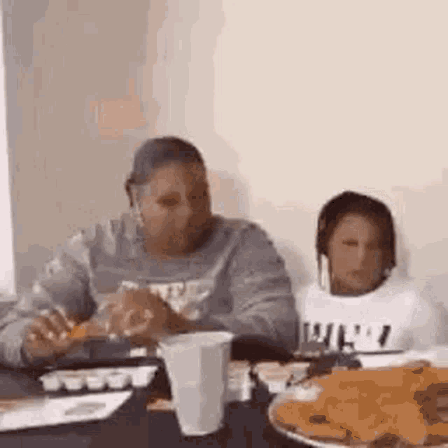 a woman and a child are sitting at a table with plates of food .