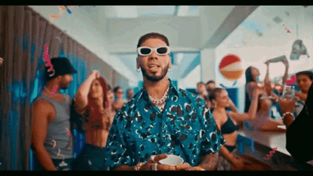 a man wearing sunglasses stands in front of a crowd