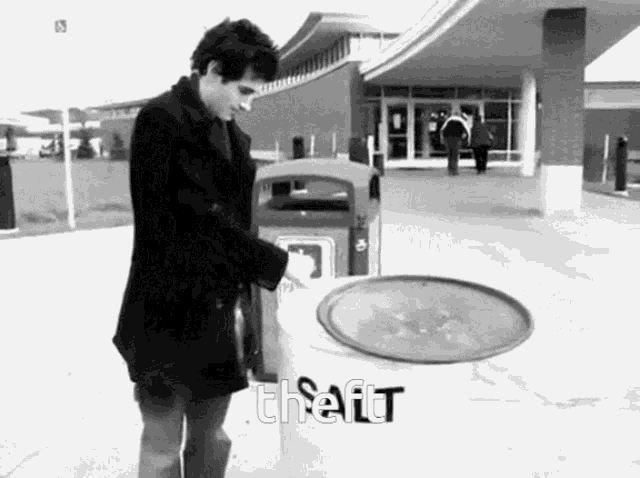 a black and white photo of a man throwing a tray into a trash can .