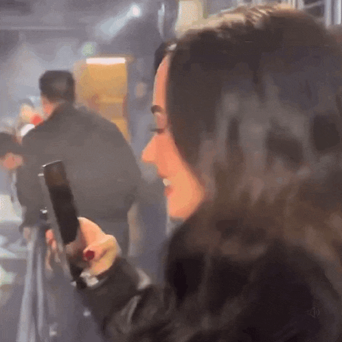 a woman is holding a cell phone in a crowded room .