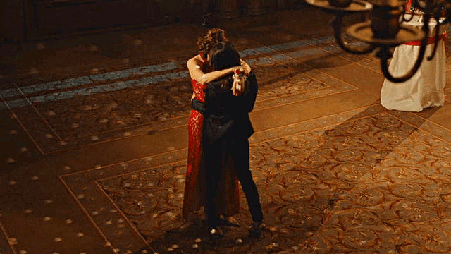 a woman in a red dress is hugging another woman in a black suit