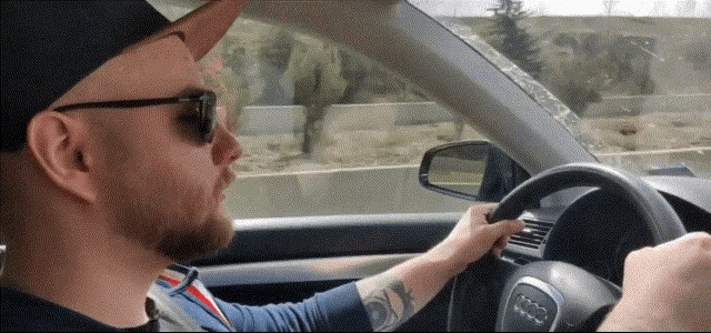 a man in a hat and sunglasses is driving an audi
