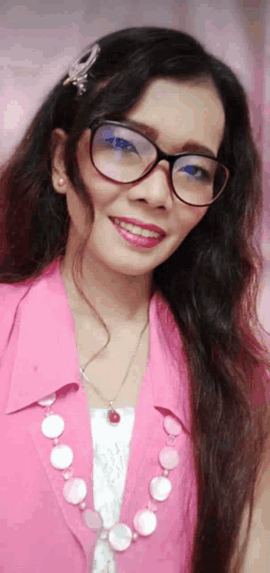 a woman wearing glasses and a pink shirt smiles