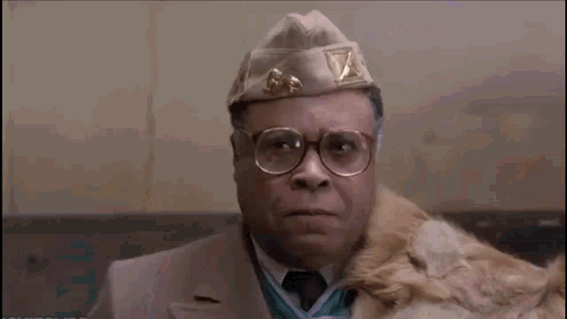 two men are talking to each other in a room and one of them is wearing a crown .