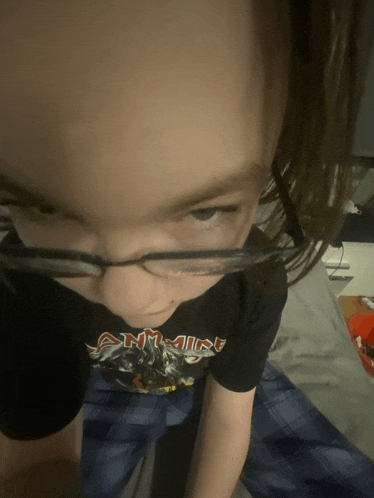 a young boy wearing glasses and a shirt that says iron maiden on it