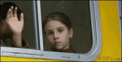 a girl is waving from the window of a yellow bus .