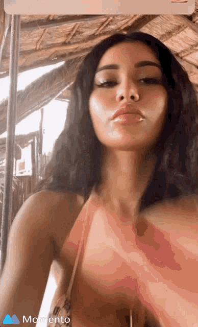 a woman in a bikini is taking a selfie with the word momento in the corner
