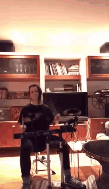 a woman is playing drums in front of a television