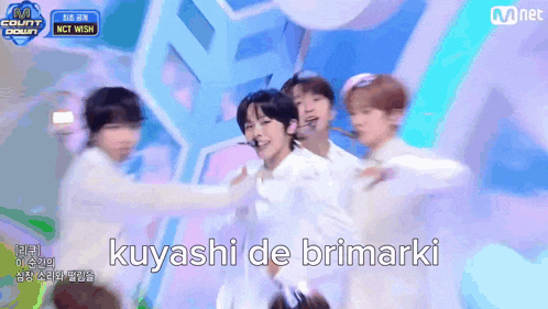 a group of young men are performing on a stage and the words kuyashi de brimarki are on the bottom of the screen