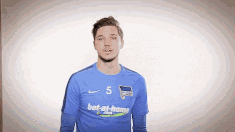 a man wearing a blue bet-at-home shirt