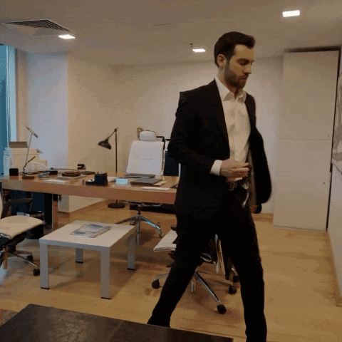 a man in a suit and white shirt is walking through an office
