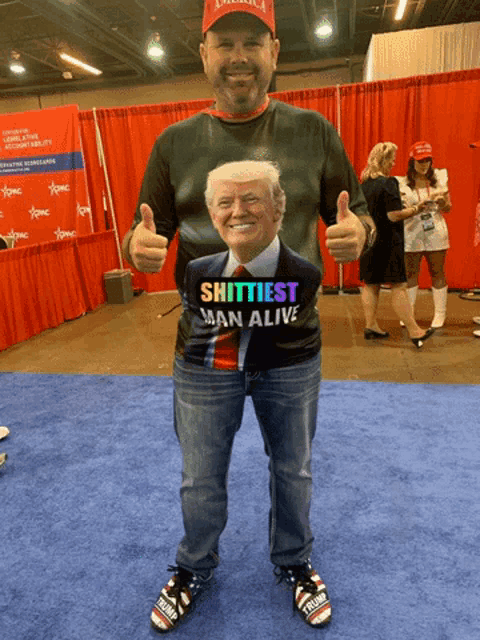 a man wears a shirt that says shittiest man alive