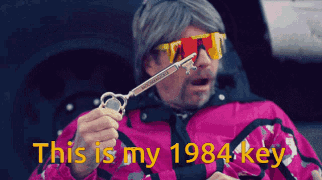 a man in a pink jacket is holding a key that says 1984 key