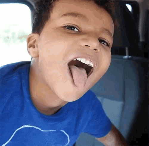 a young boy sticking his tongue out in a car