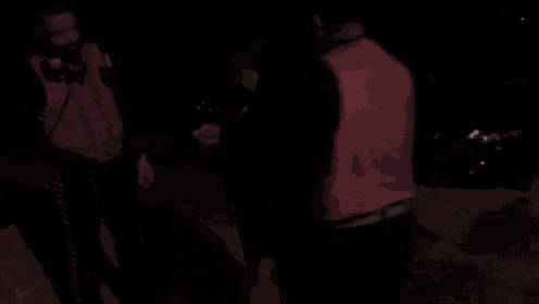 a group of people are walking down a dark street at night holding hands .