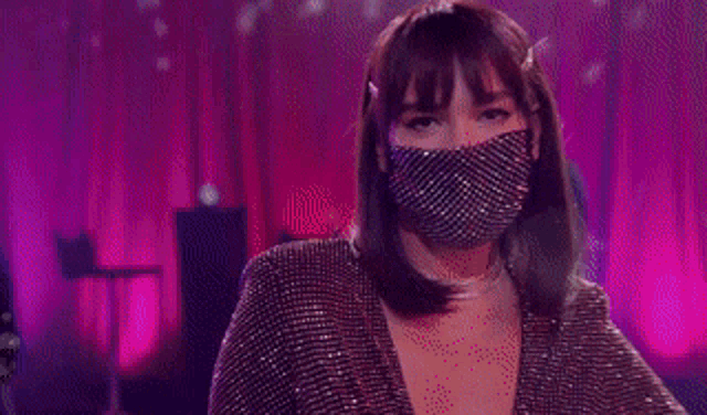 a woman wearing a mask is dancing on a stage in front of a crowd .