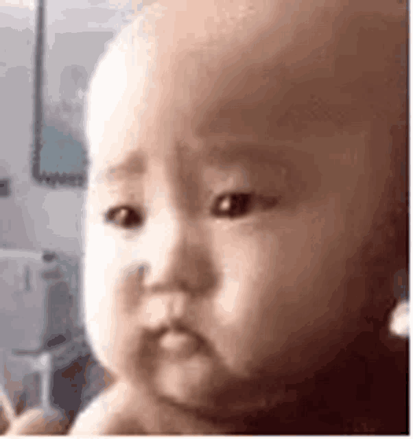 a close up of a baby 's face with a serious look on his face .