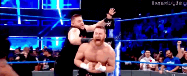 two men are wrestling in a wrestling ring and one of them is holding the other man 's head .