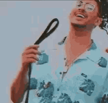 a man wearing glasses and a blue shirt is holding a cane and smiling .