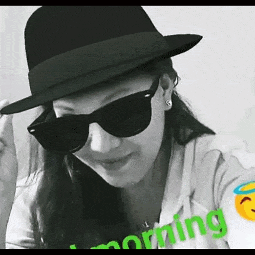 a woman wearing a hat and sunglasses has the word morning written on her shirt