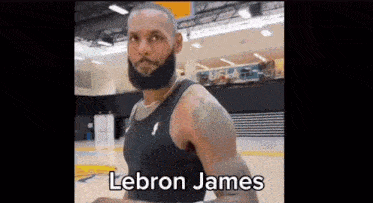 a basketball player with a beard is standing on a basketball court in a gym .