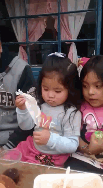 a little girl wearing a shirt that says love is eating something