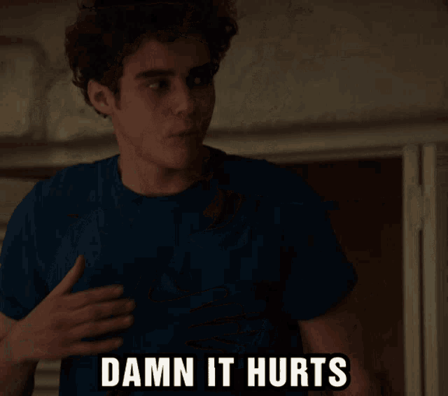 a man in a blue shirt has his hand on his chest and the words " damn it hurts " above him
