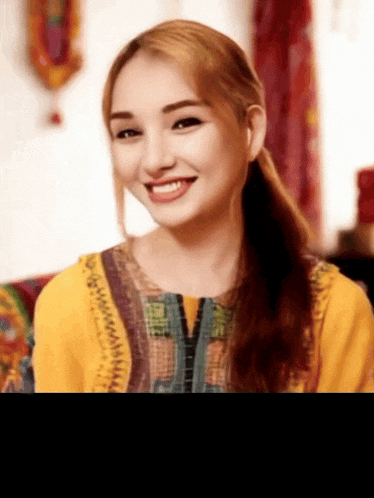 a woman wearing a yellow shirt with a zipper on the front smiles for the camera