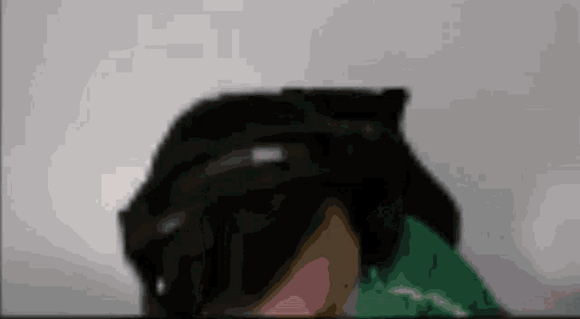 a blurry picture of a person wearing a black hat and a green shirt