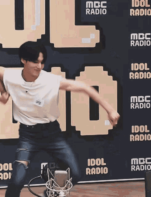 a man is dancing in front of a wall that says idol radio