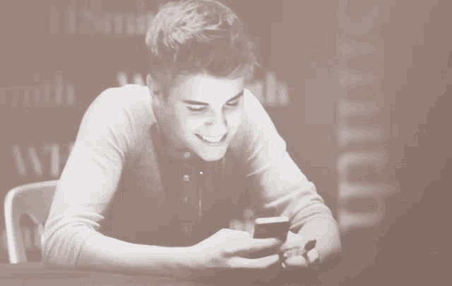 a man is smiling while looking at a cell phone
