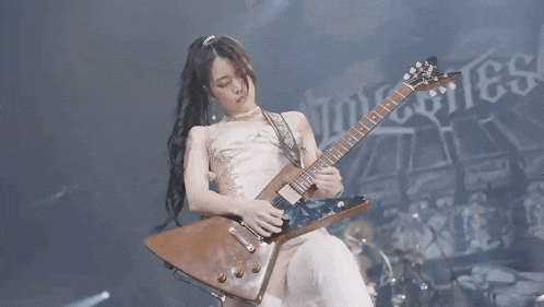 a woman in a white dress is playing a purple guitar on stage