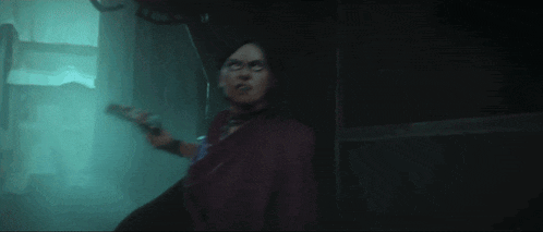 a woman in a purple dress is standing in a dark room .