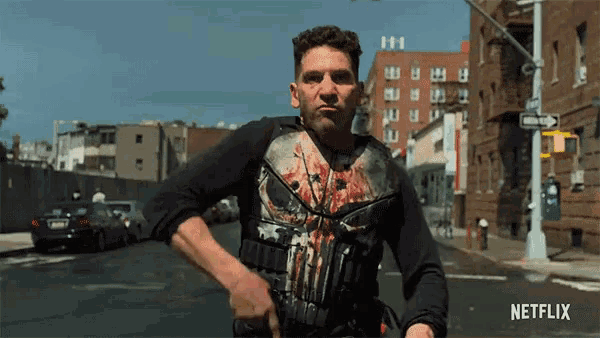 a man in a punisher shirt is walking down a street