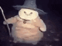 a stuffed animal is wearing a witch hat and holding a stick .
