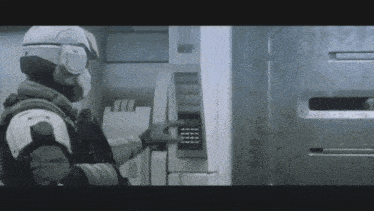 a man wearing a helmet and goggles is using an atm machine